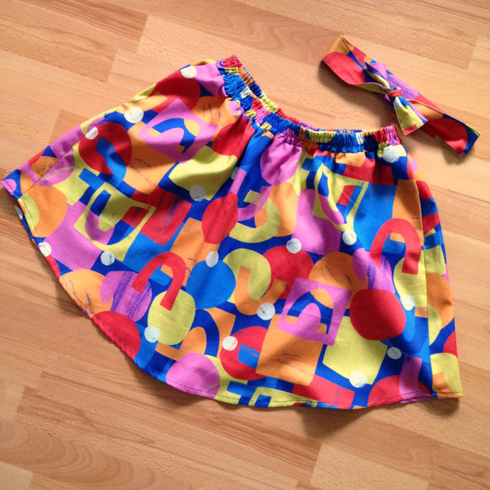 Flat lay of brightly coloured geometric patterned skirt with matching headband.
