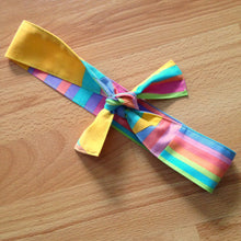 Load image into Gallery viewer, Candy coloured stripe headband tied in a bow. Has patchwork that make the stripes go in different directions.
