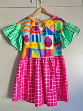 Load image into Gallery viewer, Dress with multicoloured geometric print bodice and pockets, frilly green and blue gingham sleeves and hot pink check skirt. Worn with green tights.
